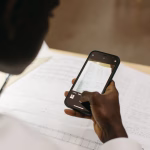 A person holding a smartphone over a paper document.