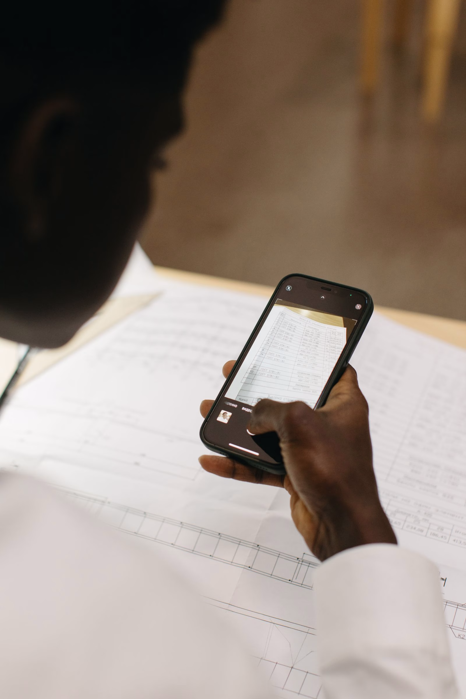 A person holding a smartphone over a paper document.