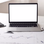 An open laptop with financial documents on a desk.