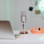 A microphone, headphones and laptop in a desk workspace.