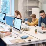 Colleagues working together at computers in a shared office.