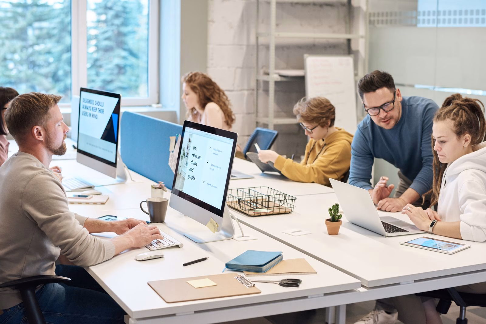Colleagues working together at computers in a shared office.