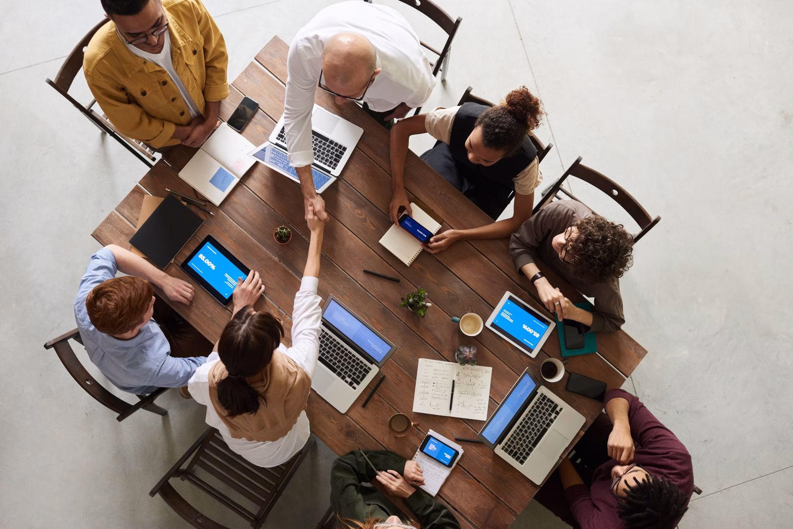 An office team discussing documents and laptops around a large table.